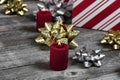 Close up of a burning red candle with gift boxes and silver or gold bow ribbon decorations on rustic wooden planks for a merry Royalty Free Stock Photo