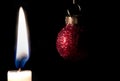 Closeup burning candle christmas ball black background