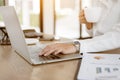 Close up business hands typing on laptop and holding coffee cup