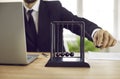 Businessman sitting at office desk with laptop and playing with Newton's pendulum Royalty Free Stock Photo