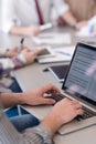 close up of business man hands typing on laptop with team on meeting in background Royalty Free Stock Photo