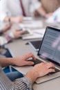 close up of business man hands typing on laptop with team on meeting in background Royalty Free Stock Photo