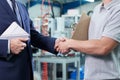 Close Up Of Business Owner With Digital Tablet In Factory Shaking Hands With Engineer