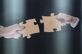 Close-up of business partners putting together white puzzle pieces on black background Royalty Free Stock Photo