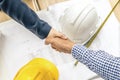 Business people handshaking at background over helmets, documents, worker tool