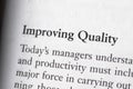 Close-up of a business textbook with the term 'improving quality' highlighted and focused