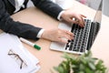 Close up of business woman hands typing on laptop computer in the white colored office.