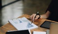 Close up business woman holding pen and pointing paper chart summary analyzing annual business report with using laptop Royalty Free Stock Photo