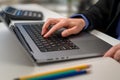 Close-up of a business woman's hand working on a laptop computer on a desk in a home office, freelancer