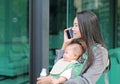 Close up business woman working by telephone with carrying her infant and holding her child`s milk bottle. Busy mother hurrying i