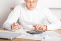 Close up of businessman or accountant hand holding pen working on calculator accountancy document and laptop computer at office, Royalty Free Stock Photo