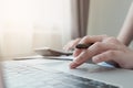 Close up of businessman or accountant hand holding pencil working on calculator to calculate financial data report, accountancy