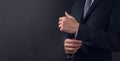 Close up of businessman in black suit and adjusting coat of arms, black background. Copy space for advertising.