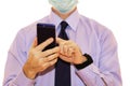 Close-up - businessman in a blue shirt and protective medical mask holds a smartphone in his hand