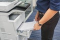 Businessman in dark blue shirt insert A4 paper sheet into office printer tray Royalty Free Stock Photo