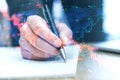 Close up of businessman hand doing finance paperwork on desk with falling forex chart arrows on blurry background. Financial