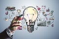 Close up of businessman hand drawing creative business sketch with huge light bulb and other icons. Idea, innovation and financial Royalty Free Stock Photo