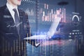 Close up of businessman hand holding laptop with creative global forex chart on blurry office interior background. Concept of