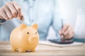 Close up businessman hand putting money coin into piggy for saving money, budget, investment or strategy for personal savings