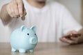 Close up businessman hand putting money coin into piggy for saving money, budget, investment or strategy for personal savings