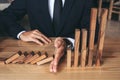 Close up of businessman hand Stopping Falling wooden Dominoes effect from continuous toppled or risk, strategy and successful int Royalty Free Stock Photo