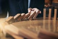 Close up of businessman hand Stopping Falling wooden Dominoes effect from continuous toppled or risk, strategy and successful int Royalty Free Stock Photo