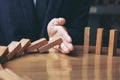 Close up of businessman hand Stopping Falling wooden Dominoes effect from continuous toppled or risk, strategy and successful int Royalty Free Stock Photo