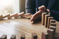 Close up of businessman hand Stopping Falling wooden Dominoes effect from continuous toppled or risk, strategy and successful int Royalty Free Stock Photo