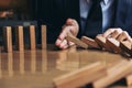 Close up of businessman hand Stopping Falling wooden Dominoes effect from continuous toppled or risk, strategy and successful int Royalty Free Stock Photo