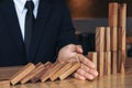 Close up of businessman hand Stopping Falling wooden Dominoes effect from continuous toppled or risk, strategy and successful int Royalty Free Stock Photo