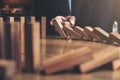 Close up of businessman hand Stopping Falling wooden Dominoes effect from continuous toppled or risk, strategy and successful int Royalty Free Stock Photo