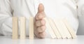 Close up of businessman hand Stopping Falling wooden Dominoes effect from continuous toppled or risk, strategy and successful Royalty Free Stock Photo