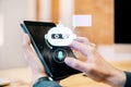 Close up of businessman hand using digital pad with glowing robot head on background. Chat bot and customer service concept