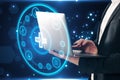 Close up of businessman hand using laptop with creative round medical interface with cross and other icons on blue background. Royalty Free Stock Photo