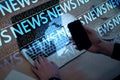 Close up of businessman hand using laptop and mobile phone on blurry blue breaking news pattern background. Headline,