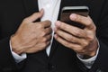 Close-up businessman hand using smart phone, with another hand holding suit collar