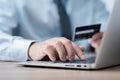 Close up of businessman hands holding a credit card and making a purchase using a laptop