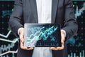 Close up of businessman hands holding tablet with growing forex chart arrow and icon on blurry dark background. Financial growth, Royalty Free Stock Photo