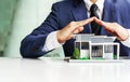 Close up businessman hands protecting modern house model on modern office at desk table Royalty Free Stock Photo