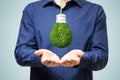 Close up of businessman holding abstract green grass light bulb on background. Eco concept and energy concept Royalty Free Stock Photo