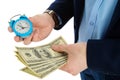 Close up of businessman holding a clock and one stack of cash in hand, time and money concept. Making right decision.