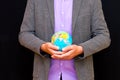 Close up of businessman holding digital globe in palm global business communications concept.Black wall Royalty Free Stock Photo
