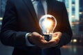 Close up of businessman holding light bulb in his hand. Idea concept, Businessman on blurred background using glowing lightbulb Royalty Free Stock Photo