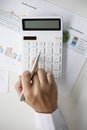 Close-up of a businessman holding a pen and pressing a white calculator. Royalty Free Stock Photo