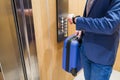 Business traveler holding baggage and checking time on his watch while standing in elevator Royalty Free Stock Photo