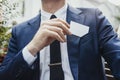 Close up of businessman putting blank business card in his blue jacket pocket. Royalty Free Stock Photo