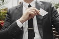 Close up of businessman putting blank business card in his jacket pocket. Royalty Free Stock Photo