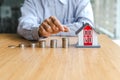 Close up businessman putting coin increase on coins stacking with house model