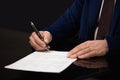 Close up of businessman sitting at table and signing document Royalty Free Stock Photo