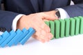 Close-up Of Businessman Stopping The Effect Of Domino With Hand